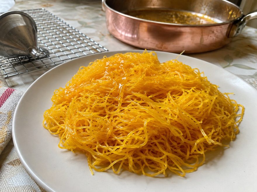 Huevos hilados: hebras doradas de yema cuajada en almíbar, en un plato blanco